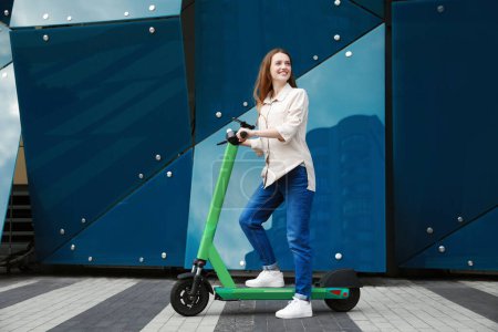 Photo for Happy woman with modern electric kick scooter on city street - Royalty Free Image