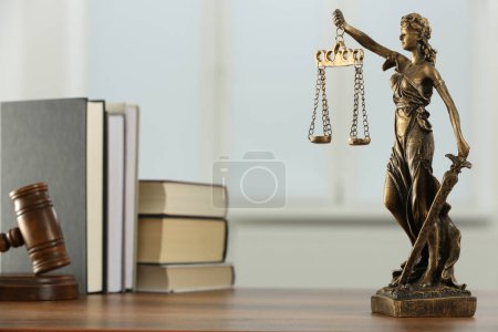 Gerechtigkeitsfigur, Hammer und Bücher auf Holztisch drinnen. Symbol der rechtlichen Gleichbehandlung