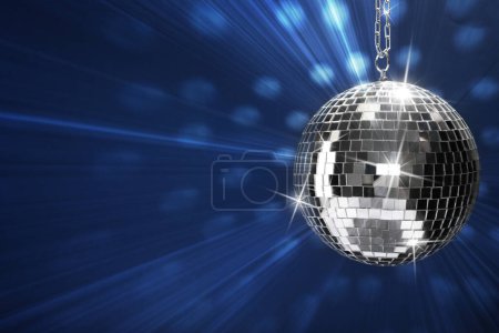 Shiny bright disco ball on blue background, space for text