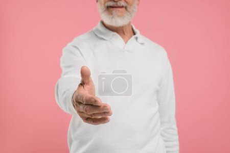 Téléchargez les photos : Homme accueillant et offrant poignée de main sur fond rose, gros plan - en image libre de droit