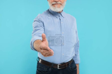 Téléchargez les photos : Homme accueillant et offrant poignée de main sur fond bleu clair, gros plan - en image libre de droit
