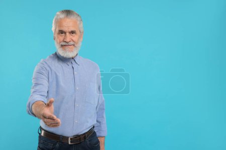 Téléchargez les photos : Senior homme accueillant et offrant poignée de main sur fond bleu clair, espace pour le texte - en image libre de droit
