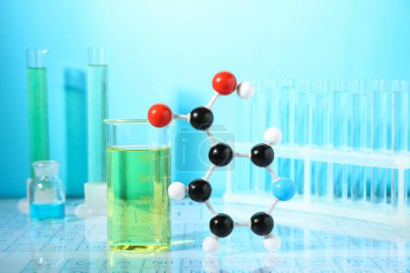 Modèle moléculaire et verrerie de laboratoire sur fond bleu clair