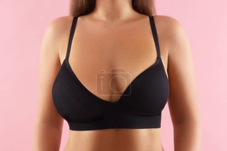 Woman with breast asymmetry on pink background, closeup