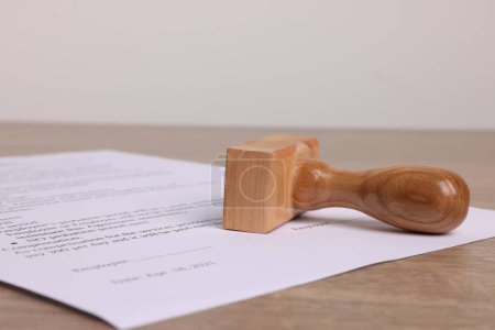 One stamp tool and document on wooden table, closeup