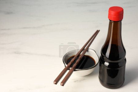 Photo for Soy sauce and chopsticks on white table, space for text - Royalty Free Image