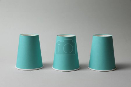 Téléchargez les photos : Trois tasses en papier sur fond gris clair. Jeu de Thimblerig - en image libre de droit