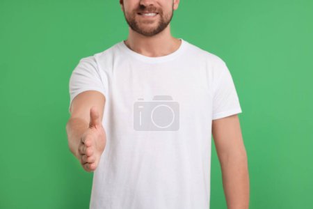 Téléchargez les photos : Homme accueillant et offrant poignée de main sur fond vert, gros plan - en image libre de droit