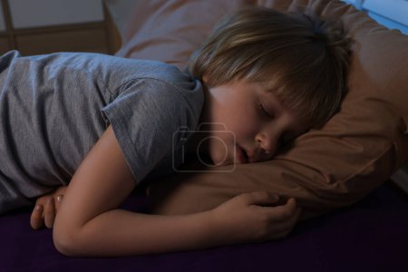 Photo for Little boy snoring while sleeping on bed at night - Royalty Free Image