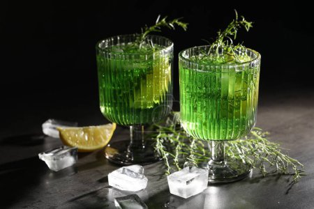 Photo for Glasses of homemade refreshing tarragon drink, ice cubes and sprigs on grey table - Royalty Free Image