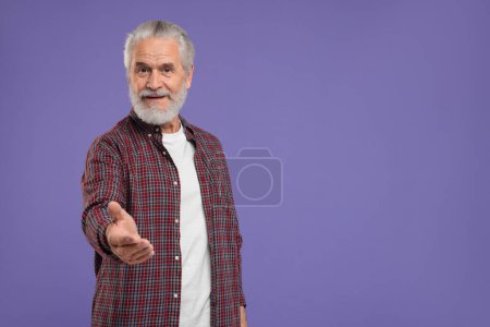 Téléchargez les photos : Senior homme accueillant et offrant poignée de main sur fond violet, espace pour le texte - en image libre de droit