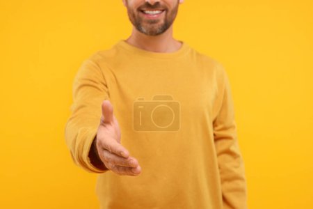 Téléchargez les photos : Homme accueillant et offrant poignée de main sur fond orange, gros plan - en image libre de droit