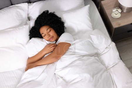 Téléchargez les photos : Belle jeune femme dormant dans un lit doux à la maison, vue ci-dessus - en image libre de droit