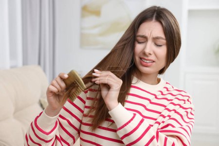 Upset woman brushing her hair at home. Alopecia problem