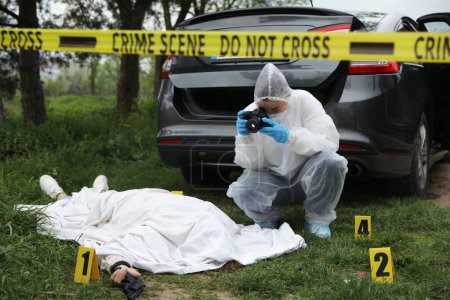 Foto de Criminólogo tomando fotos de cadáver en la escena del crimen al aire libre - Imagen libre de derechos