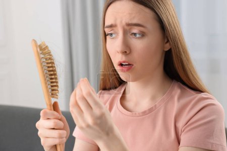 Mujer emocional desenredar su cabello perdido de cepillo en casa. Problema de alopecia