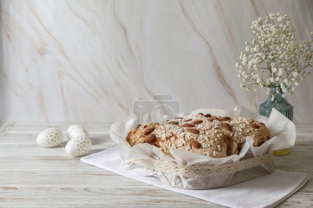 Foto de Delicioso pastel italiano de paloma de Pascua (Colomba di Pasqua tradicional), huevos decorados y flores en la mesa de madera blanca. Espacio para texto - Imagen libre de derechos