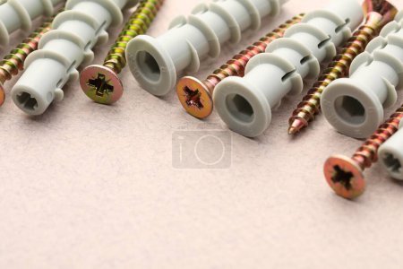 Photo for Many metal screws and dowels on beige textured table, closeup. Space for text - Royalty Free Image