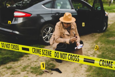 Foto de Detective profesional examinando la escena del crimen al aire libre, se centran en cinta amarilla - Imagen libre de derechos