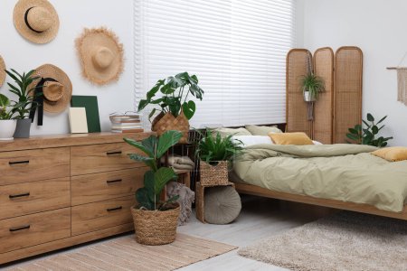 Téléchargez les photos : Lit confortable et belles plantes d'intérieur vertes dans la chambre - en image libre de droit