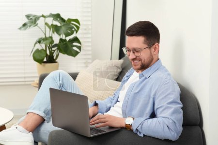Téléchargez les photos : Homme utilisant un ordinateur portable sur le canapé à la maison - en image libre de droit