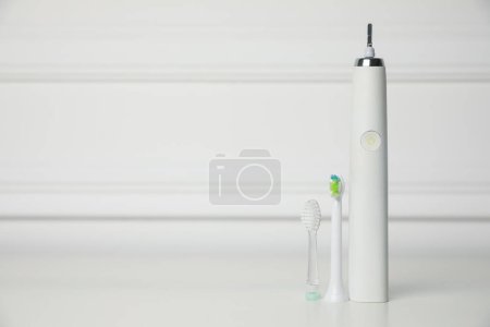 Photo for Electric toothbrush and replacement brush heads on white background, space for text - Royalty Free Image