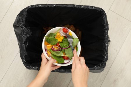 Frau wirft Gemüsesalat in Mülltonne, Draufsicht