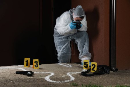 Photo for Criminologist in protective suit working at crime scene outdoors. Space for text - Royalty Free Image