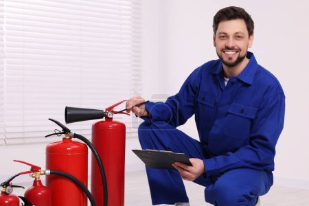 Photo for Man with clipboard checking fire extinguishers indoors - Royalty Free Image