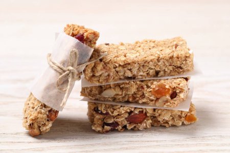 Photo for Tasty granola bars on white wooden table, closeup - Royalty Free Image