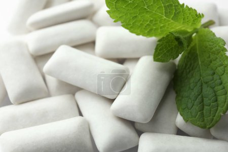 Photo for Tasty white chewing gums and mint leaves as background, closeup - Royalty Free Image