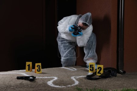 Foto de Criminólogo en traje de protección trabajando en la escena del crimen al aire libre. Espacio para texto - Imagen libre de derechos