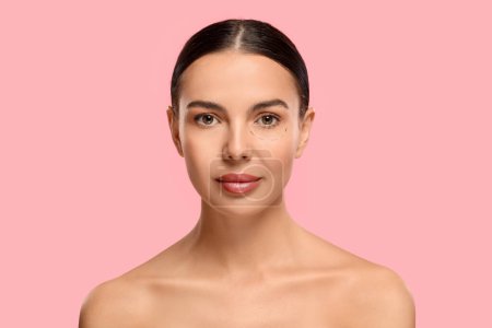 Porträt einer schönen Frau mit Markierungen vor kosmetischen Eingriffen auf rosa Hintergrund