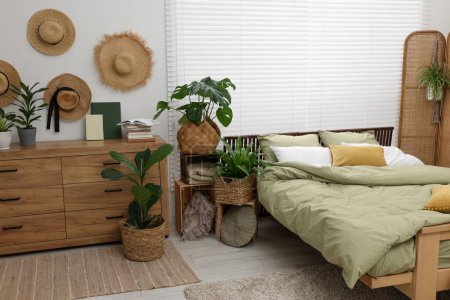 Téléchargez les photos : Lit confortable et belles plantes d'intérieur vertes dans la chambre - en image libre de droit