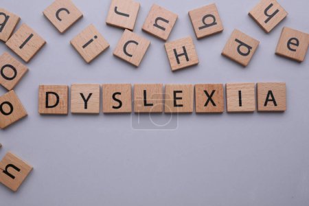 Foto de Baldosas de madera con la palabra Dislexia sobre fondo gris claro, disposición plana. Espacio para texto - Imagen libre de derechos