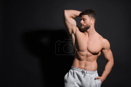 Foto de Hombre musculoso guapo sobre fondo negro, espacio para el texto. Cuerpo sexy - Imagen libre de derechos