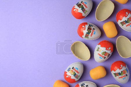 Photo for Sveti Vlas, Bulgaria - June 29, 2023: Kinder Surprise Eggs and plastic capsules on violet background, flat lay. Space for text - Royalty Free Image