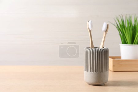 Téléchargez les photos : Brosses à dents en bambou dans le support sur table en bois, espace pour le texte - en image libre de droit