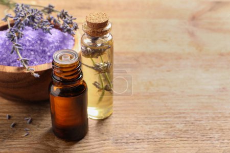 Foto de Cuenco de sal marina, aceite esencial y flores de lavanda en la mesa de madera, espacio para el texto - Imagen libre de derechos
