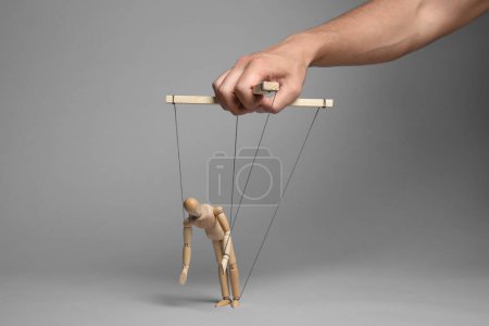 Photo for Man pulling strings of puppet on gray background, closeup - Royalty Free Image