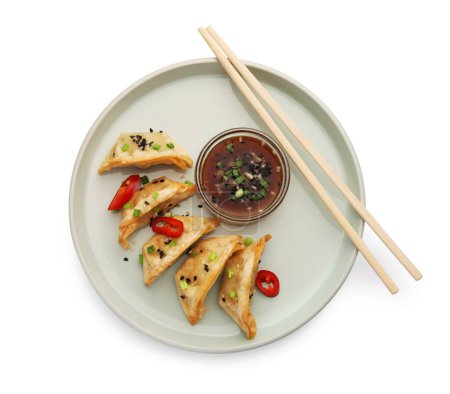 Téléchargez les photos : Délicieux gyoza (boulettes asiatiques) avec sauce, poivre, oignon, sésame et baguettes isolées sur blanc, vue sur le dessus - en image libre de droit