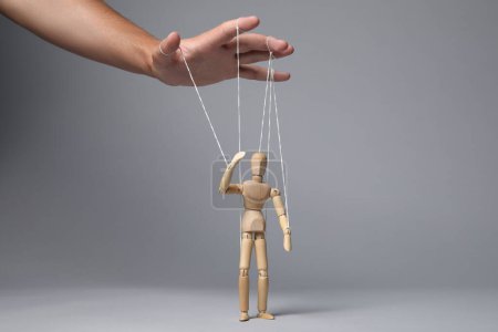 Photo for Man pulling strings of puppet on gray background, closeup - Royalty Free Image