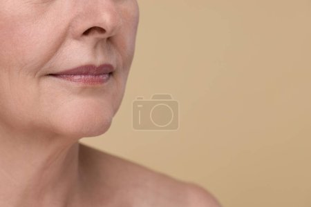 Téléchargez les photos : Femme âgée avec peau vieillissante sur fond beige, gros plan et espace pour le texte. Traitement de rajeunissement - en image libre de droit