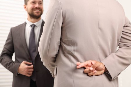 Foto de Empleado cruzando los dedos a sus espaldas mientras se reúne con el jefe en la oficina, enfoque selectivo - Imagen libre de derechos
