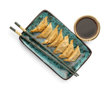 Téléchargez les photos : Délicieux gyoza (boulettes asiatiques), sauce soja et baguettes isolées sur blanc, vue de dessus - en image libre de droit