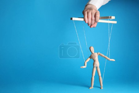Photo for Woman pulling strings of puppet on light blue background, closeup. Space for text - Royalty Free Image