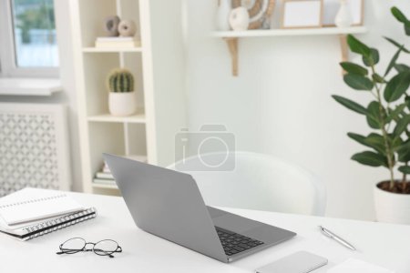 Photo for Home office. Laptop, glasses, notebooks, smartphone and pen on white desk indoors - Royalty Free Image
