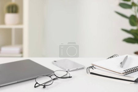 Photo for Home office. Laptop, glasses, notebooks, smartphone and pen on white desk indoors. Space for text - Royalty Free Image