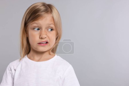 Photo for Embarrassed little girl on grey background. Space for text - Royalty Free Image