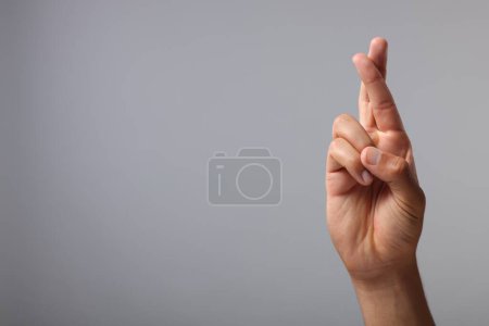 Foto de Hombre cruzando los dedos sobre fondo gris, primer plano. Espacio para texto - Imagen libre de derechos